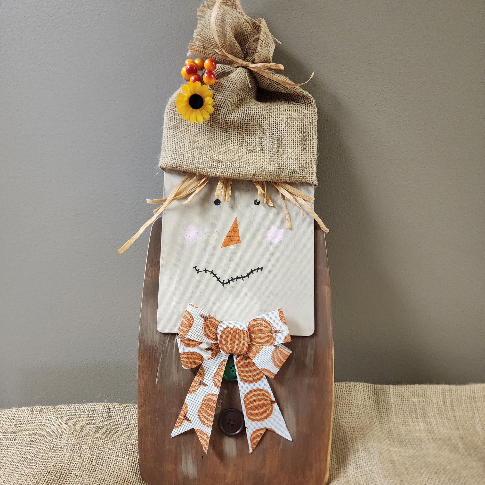 Photo of scarecrow made with two overlapping cutting boards and decorated with a Fall theme.