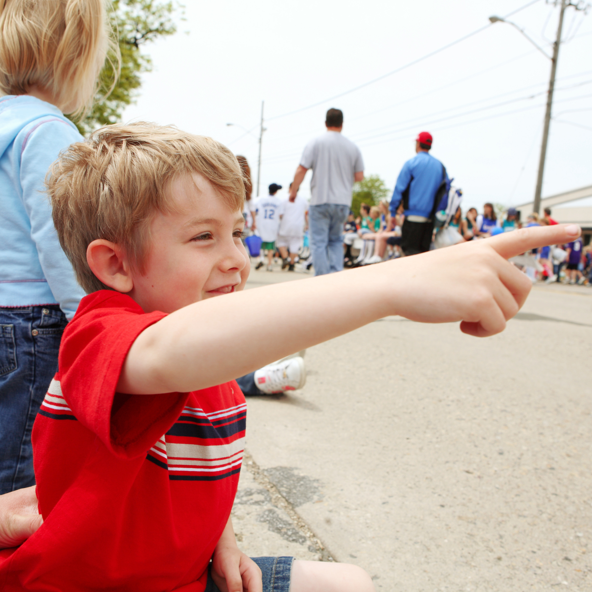 Child smiling and pointing as a parade passes by.