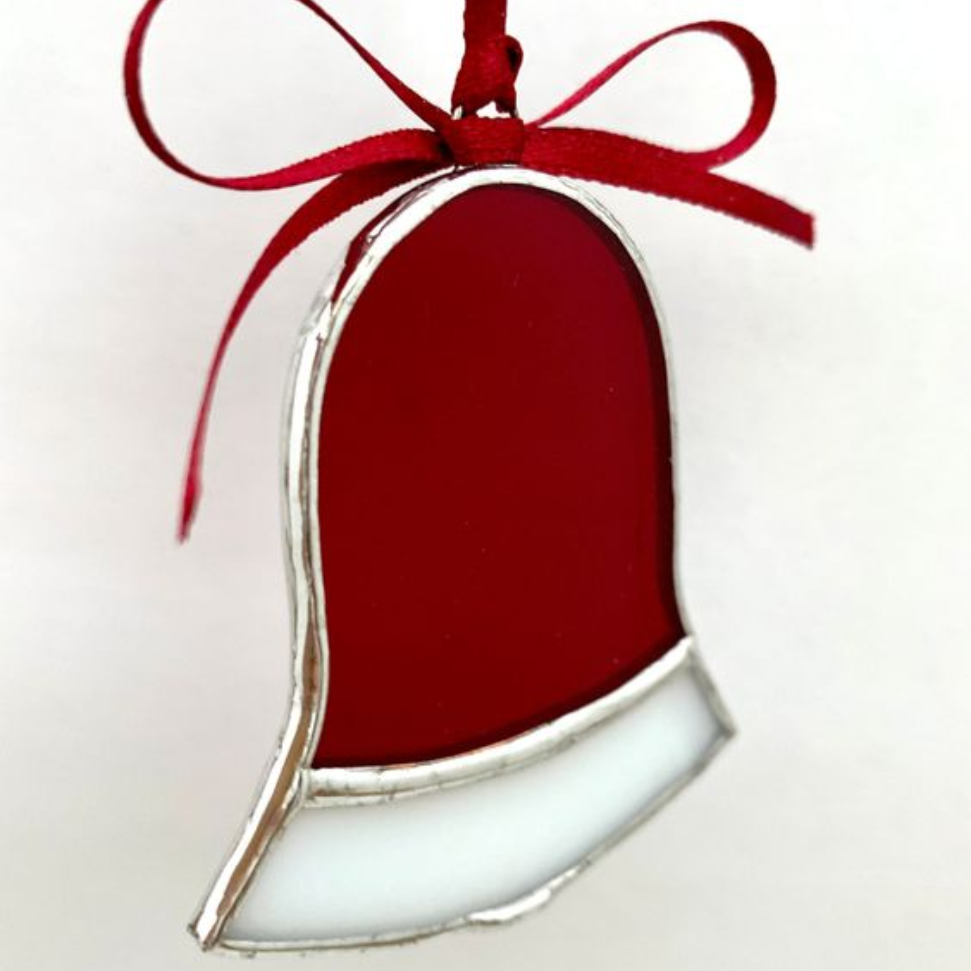 red and white holiday bell made of stained glass with a red ribbon