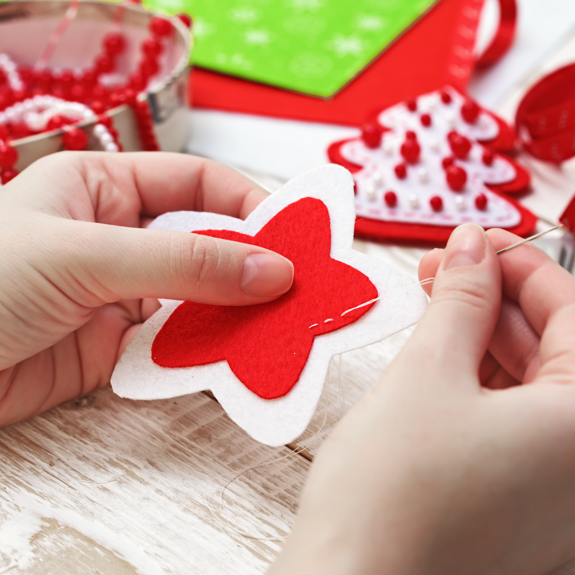 Photo of two hands sewing a felt star.