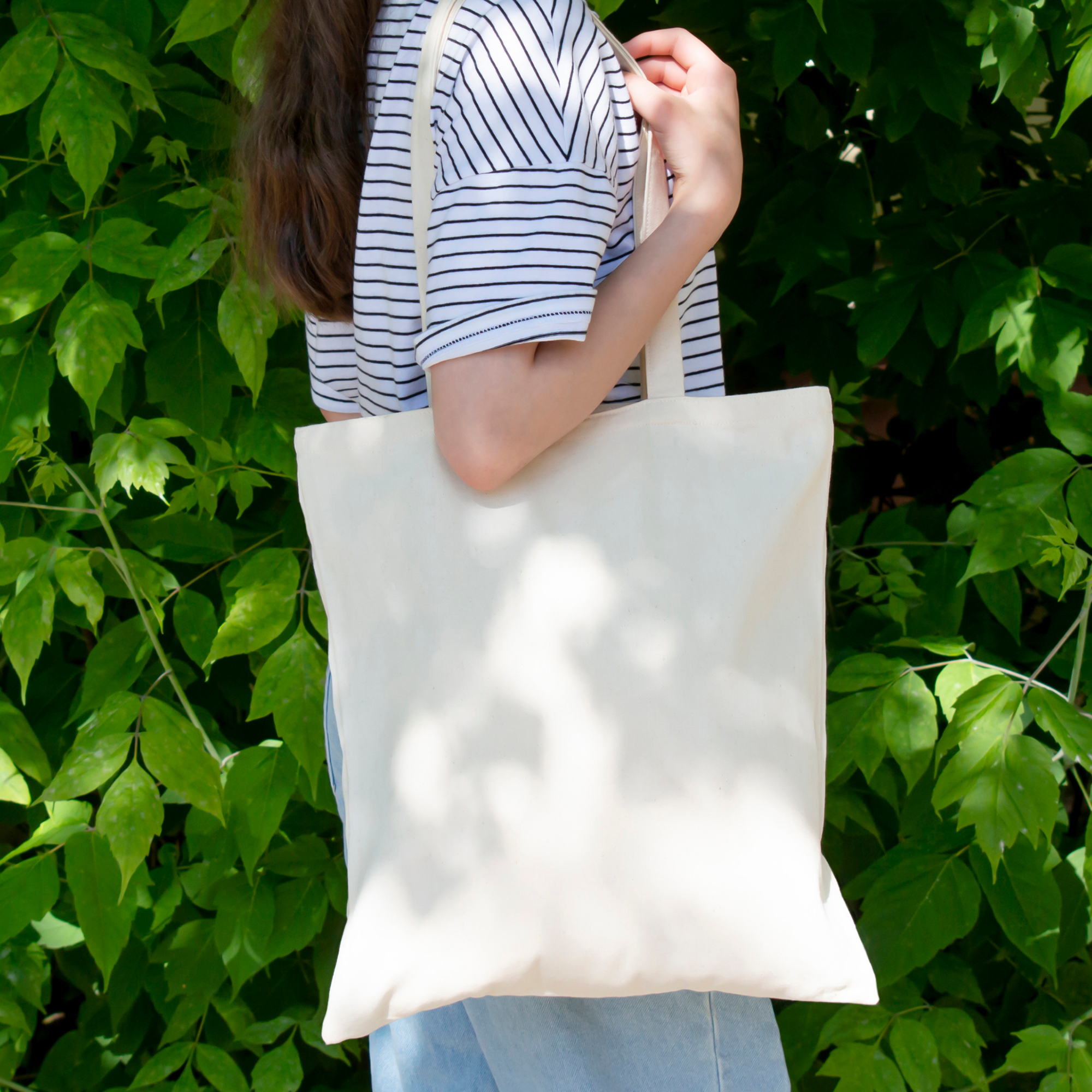 Photo of woman with a blank canvas tote on her shoulder.