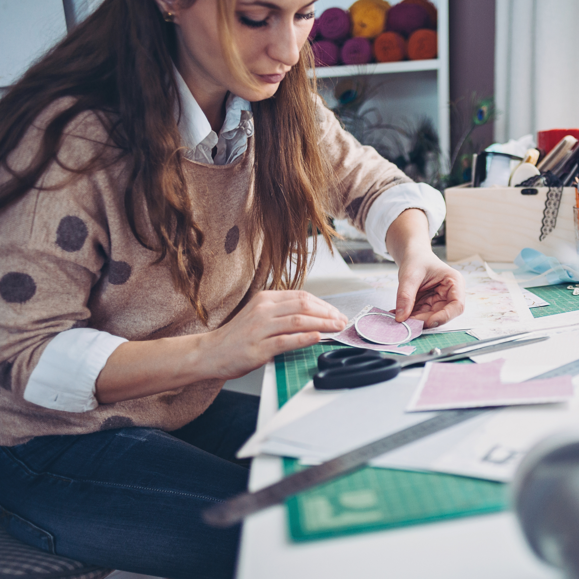 Photo of woman working with paper materials on a cutting board.