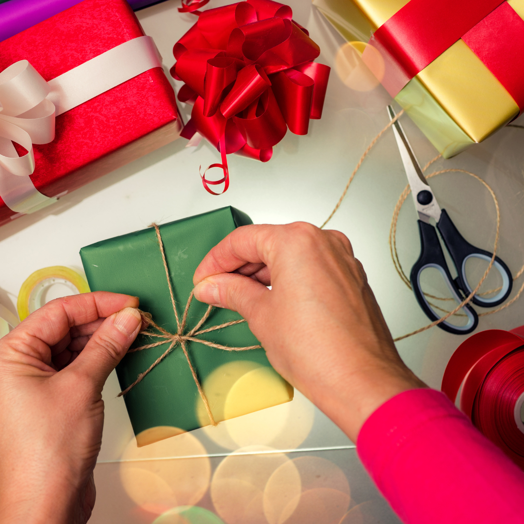 green gift package with someone tying a bow