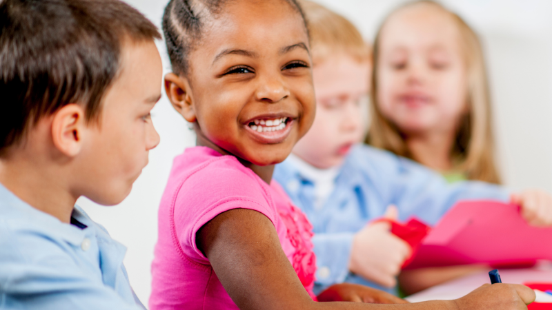 Photo of multiple children smiling and coloring.